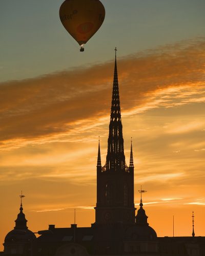 15 Jun 2006, Stockholm, Sweden --- Hot air balloon passing over Riddarholmskyrkan in Stockholm at sunset. --- Image by © Jon Hicks/Corbis